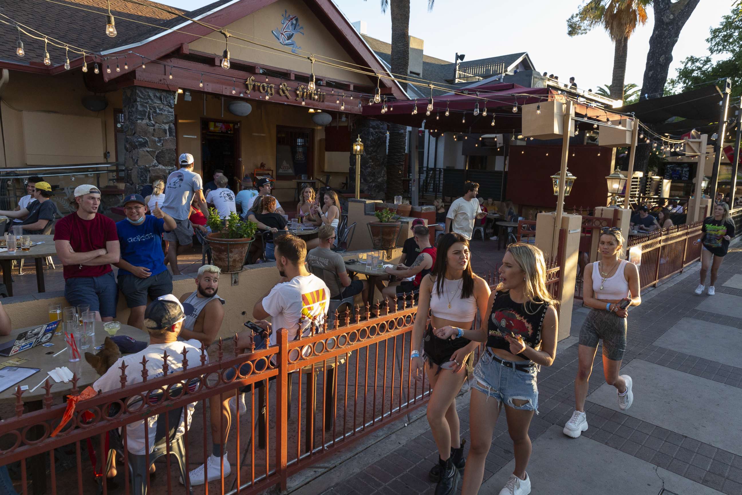 PHOTO: Pedestrians walk past customers sitting outside at a bar in Tucson, Arizona, U.S., on Monday, May 11, 2020.
