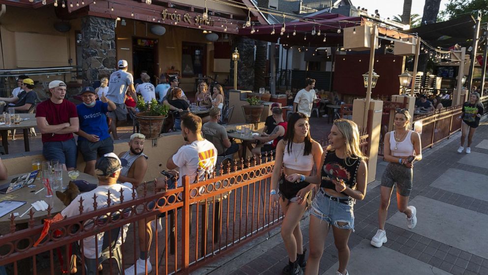 PHOTO: Pedestrians walk past customers sitting outside at a bar in Tucson, Arizona, U.S., on Monday, May 11, 2020.