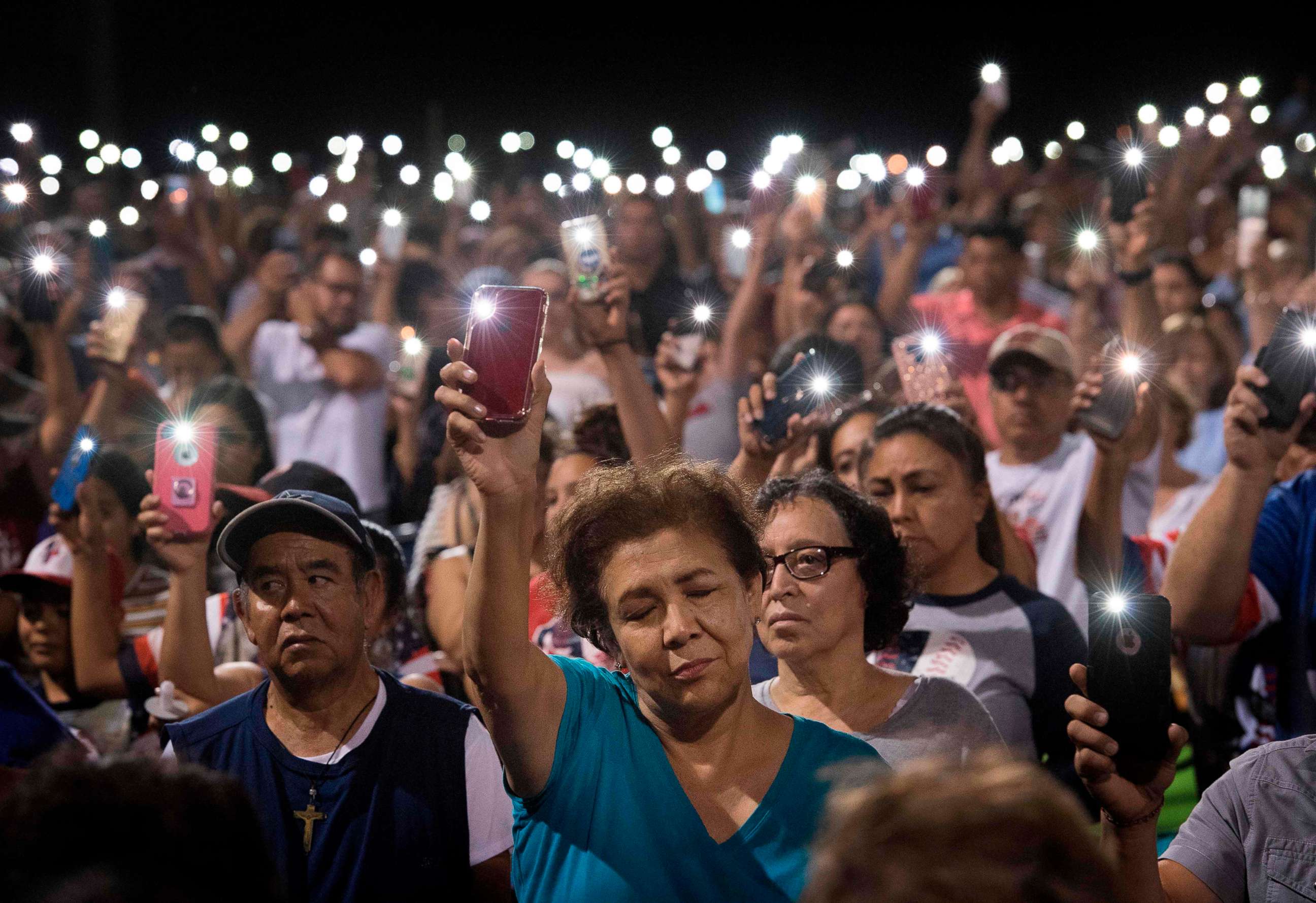 PHOTO: People hold up their phones during a prayer and candle vigil organized by the city, after a shooting at the Cielo Vista Mall Wal-Mart in El Paso, Texas, Aug. 4, 2019.
