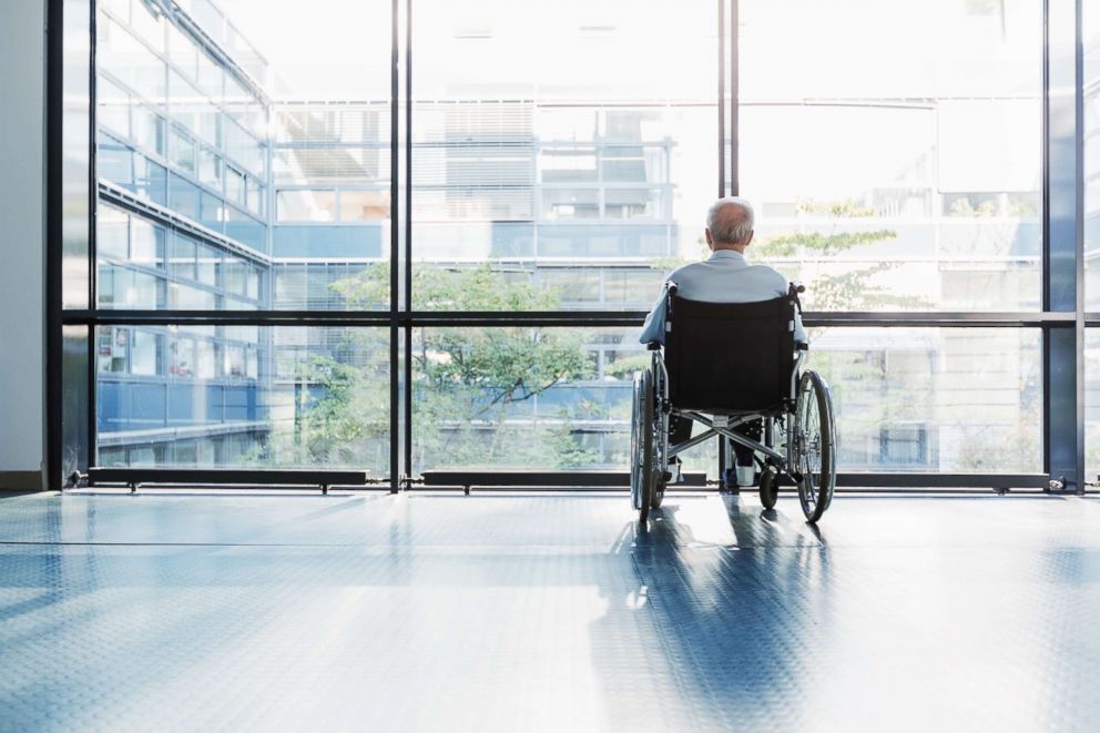 PHOTO: A senior man in a wheelchair looking out of a window in a hospital corridor appears in this undated stock photo.