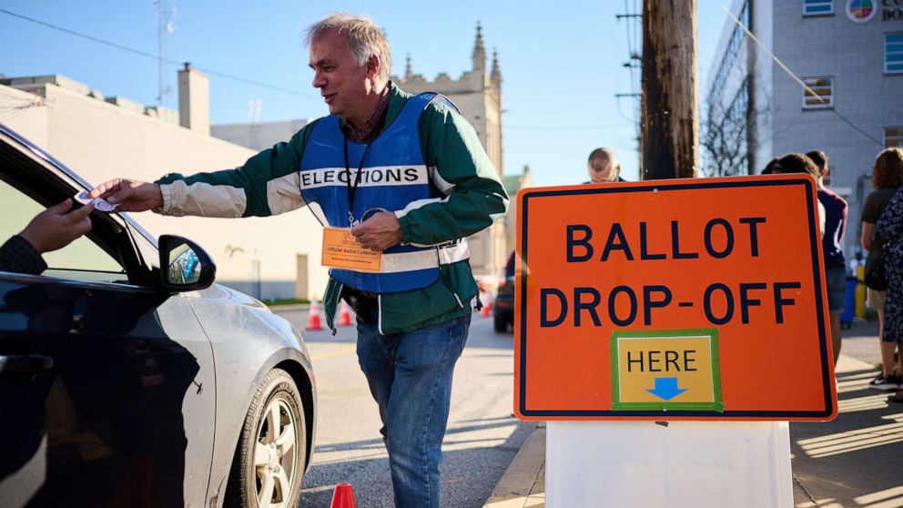 PHOTO: An official ballot collector for the Cuyahoga County Board of Elections gives a voter his 