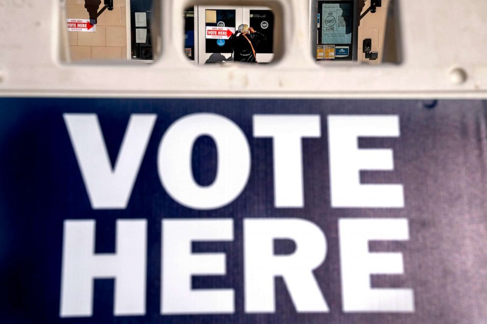 PHOTO: A woman is seen through a "vote here" sign, as she enters a polling site to vote in the midterm elections, Tuesday, Nov. 8, 2022, in Washington.