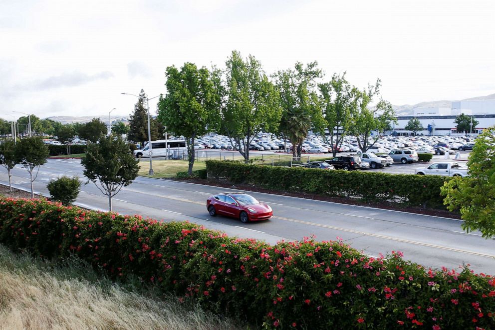 PHOTO: In this May 12, 2020, file photo, a Tesla Model 3 electric vehicle drives on Kato Road at Tesla's primary vehicle factory in Fremont, Calif.