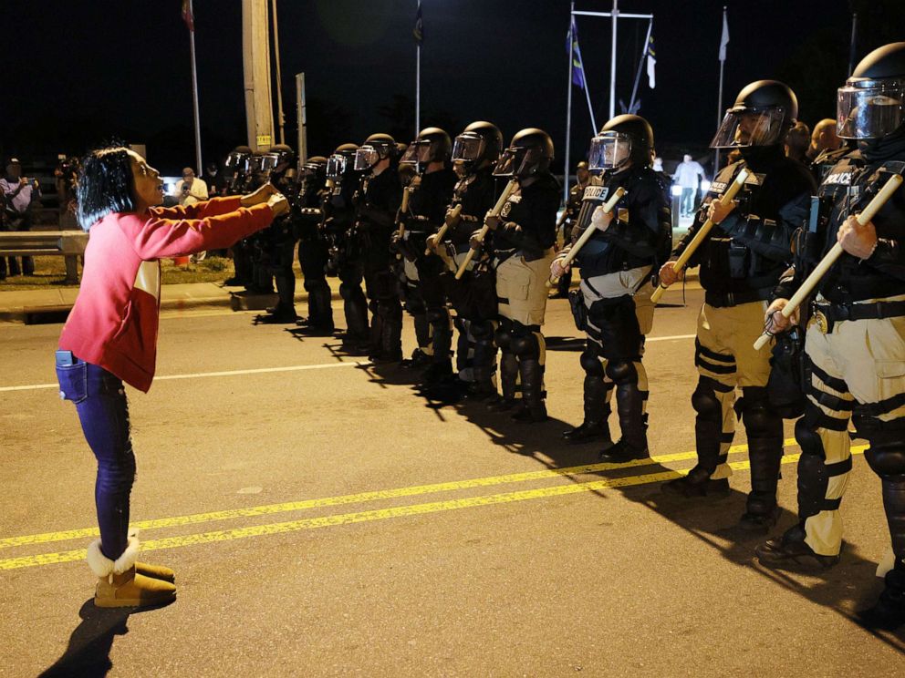 PHOTO: Patrice Revelle stands in front of police in riot gear as they force people off a street as they protest the killing of Andrew Brown Jr. on April 27, 2021 in Elizabeth City, North Carolina.