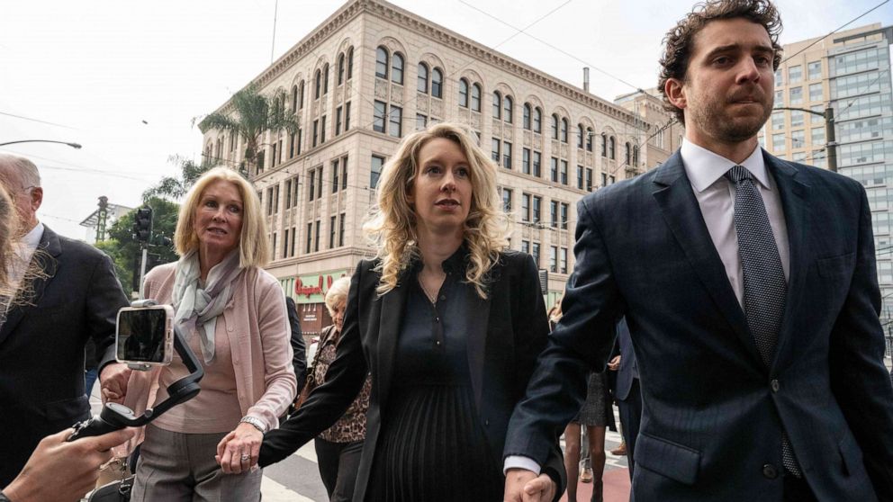 PHOTO: Elizabeth Holmes, founder and former CEO of blood testing and life sciences company Theranos, walks with her mother Noel Holmes and partner Billy Evans into the federal courthouse for her sentencing hearing on Nov. 18, 2022 in San Jose, Calif.