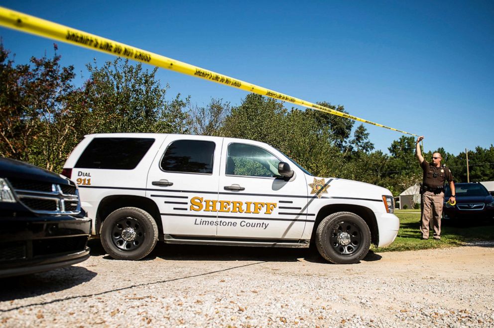 PHOTO: Sgt. Jonathan Hardiman, right, moves caution tape as a Limestone County Sheriff vehicle leaves the scene of a shooting, Sep. 3, 2019, in Elkmont, Ala.