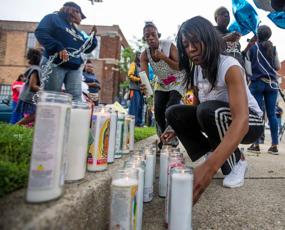 PHOTO: Sherika Logan lights candles for her uncle during a vigil for Eric Logan Monday, June 17, 2019 on Washington Street in South Bend, Ind.