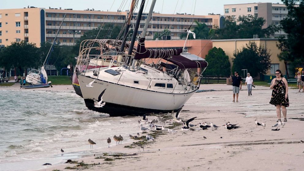 PHOTO: People walk past boats on the beach in the aftermath of Tropical Storm Eta, Nov. 12, 2020, in Gulfport, Fla.