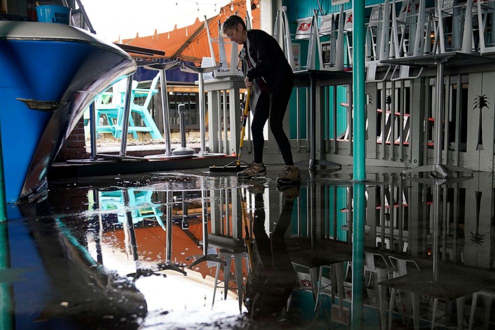 PHOTO: Kate Connell sweeps water and mud from the floor at Salty's Gulfport bar and in the aftermath of Tropical Storm Eta, Nov. 12, 2020, in Gulfport, Fla.