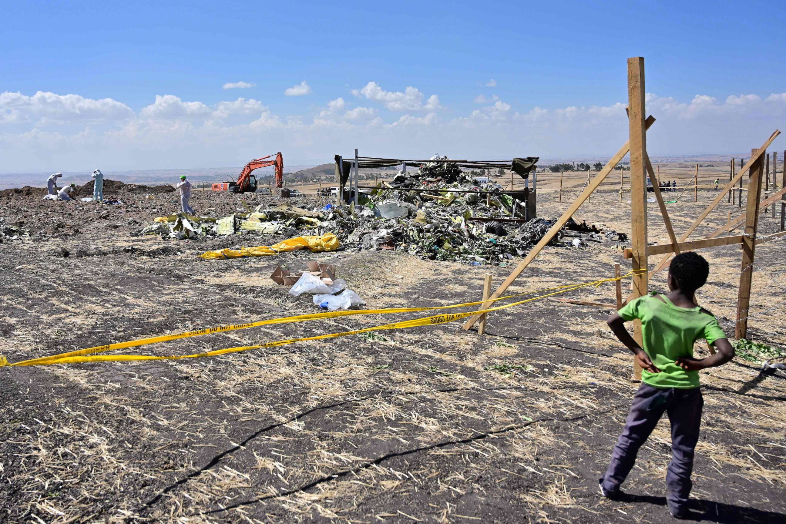 PHOTO: A boy look as forensic investigators comb the ground for DNA evidence near a pile of twisted airplane debris at the crash site of an Ethiopian airways operated Boeing 737 MAX aircraft, March 16, 2019, near Bishoftu in Ethiopia.