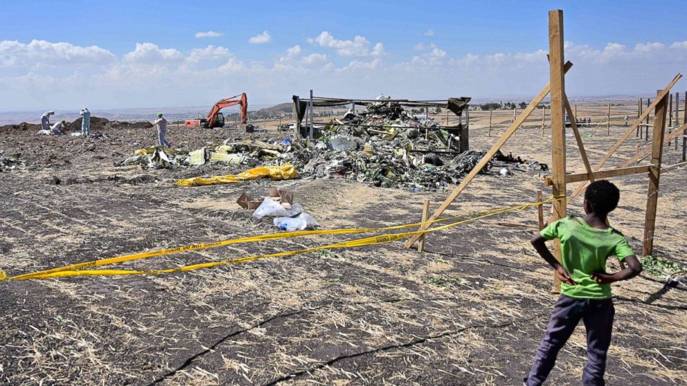 PHOTO: A boy look as forensic investigators comb the ground for DNA evidence near a pile of twisted airplane debris at the crash site of an Ethiopian airways operated Boeing 737 MAX aircraft, March 16, 2019, near Bishoftu in Ethiopia.