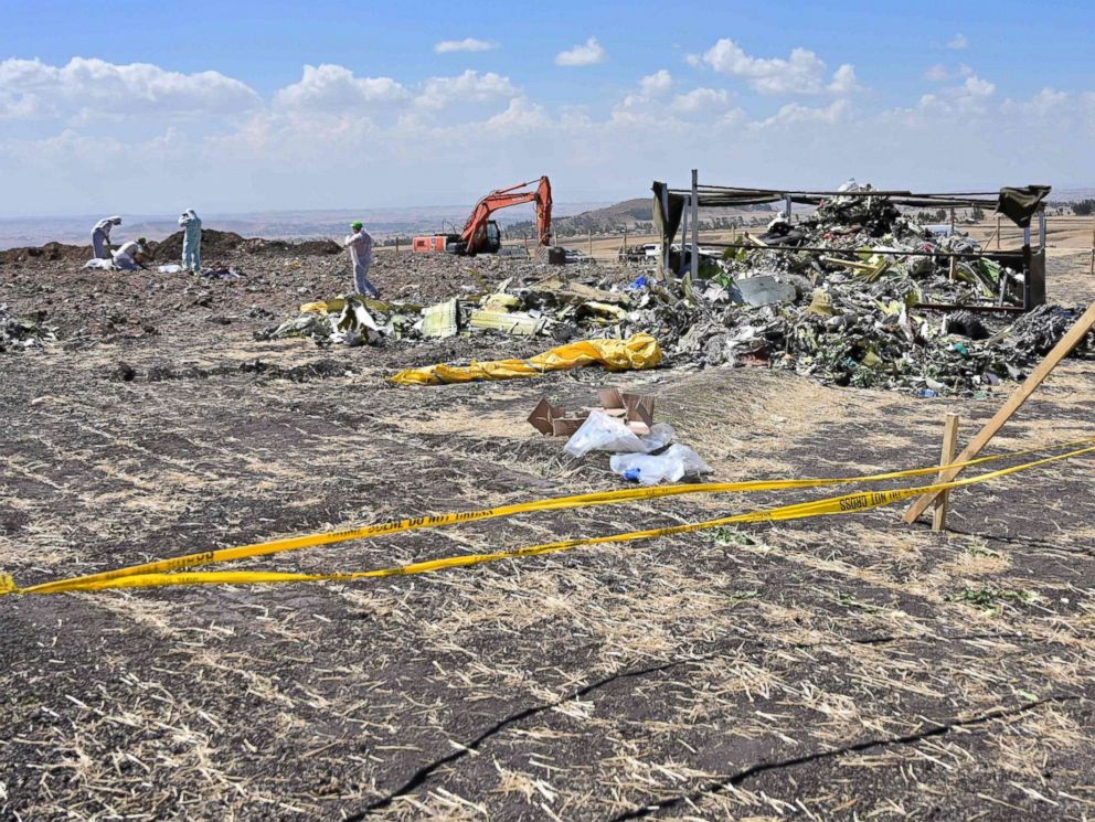 PHOTO: A boy look as forensic investigators comb the ground for DNA evidence near a pile of twisted airplane debris at the crash site of an Ethiopian airways operated Boeing 737 MAX aircraft, March 16, 2019, near Bishoftu in Ethiopia.