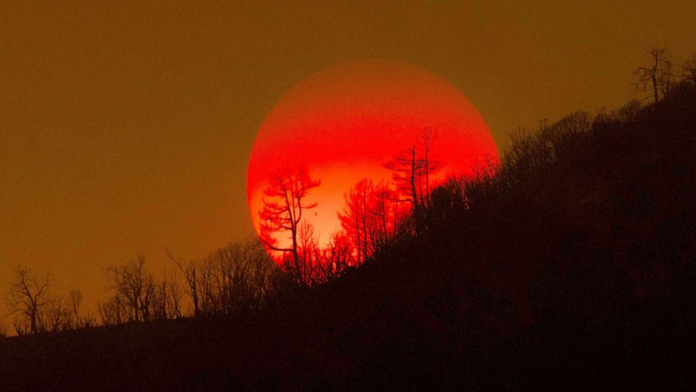 PHOTO: The sun sinks behind a smoky sky and burned forest at the Oak Fire on near Mariposa, Calif.,July 24, 2022. 