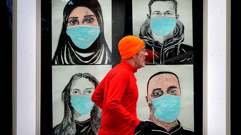 PHOTO: A runner passes by a window displaying portraits of people wearing face masks to help prevent the spread of the novel coronavirus in Lewiston, Maine, on Nov.16, 2020.