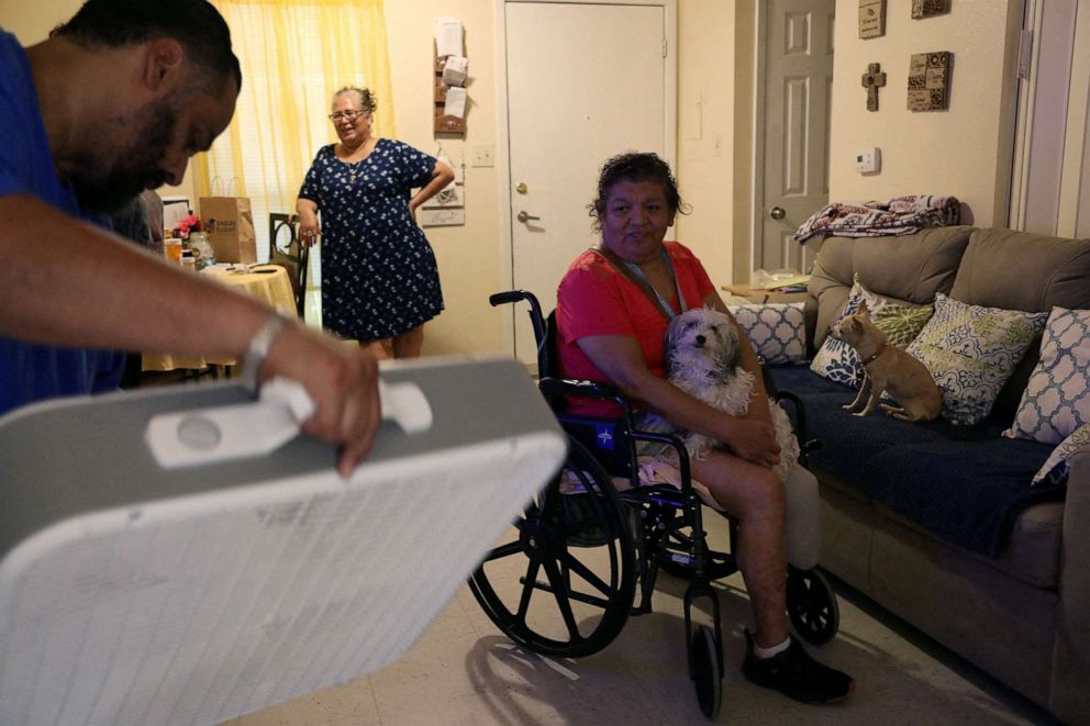 PHOTO: Jon David De Leon, with the non-profit, Eagles Flight Advocacy and Outreach, delivers a fan to Juanita Alarcon to help cope with the heat in San Antonio, Texas, July 11, 2022.