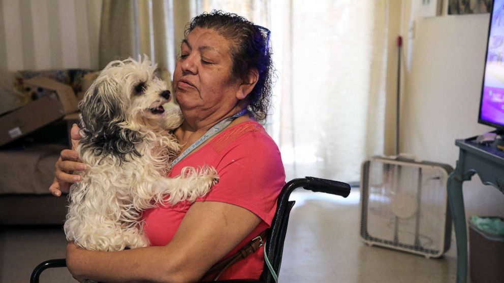 PHOTO: Juanita Alarcon holds her dog, Chloe, near a newly donated fan to help cope with the heat, in San Antonio, Texas, July 11, 2022.