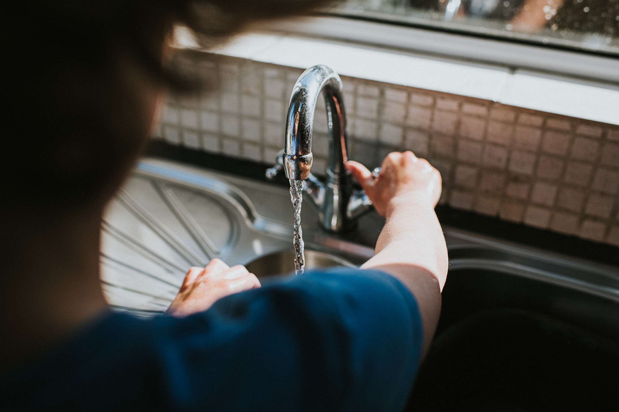 PHOTO: Someone turning the tap on to wash their hands at a kitchen sink in an undated stock photo.