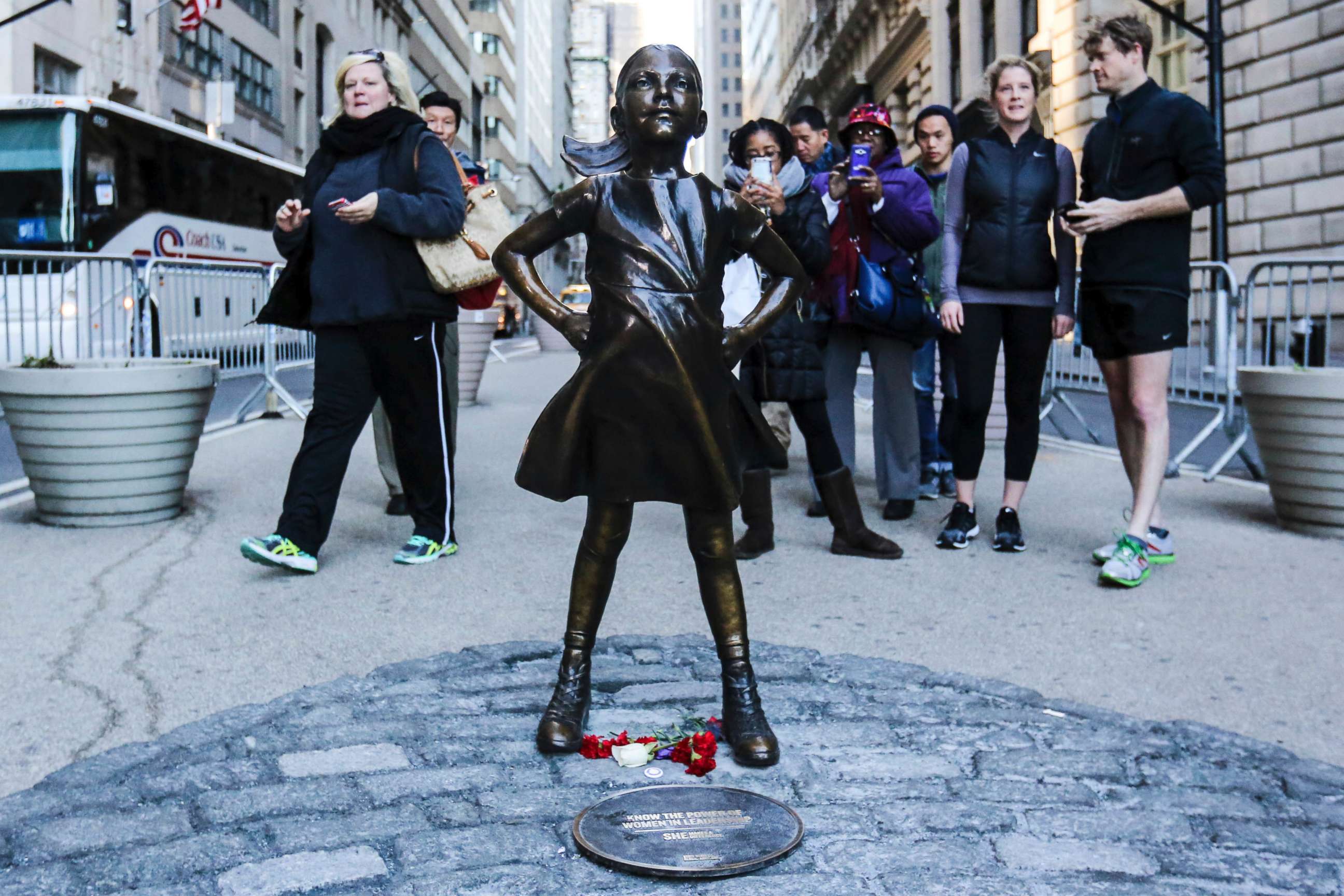 PHOTO: Tourists take photos of 'The Fearless Girl' statue as it stands across from the Wall Street's famous Charging Bull to draw attention to the gender equality and lack of female managers, March 9, 2017, in New York. 