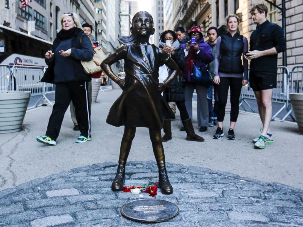 PHOTO: Tourists take photos of The Fearless Girl statue as it stands across from the Wall Streets famous Charging Bull to draw attention to the gender equality and lack of female managers, March 9, 2017, in New York.