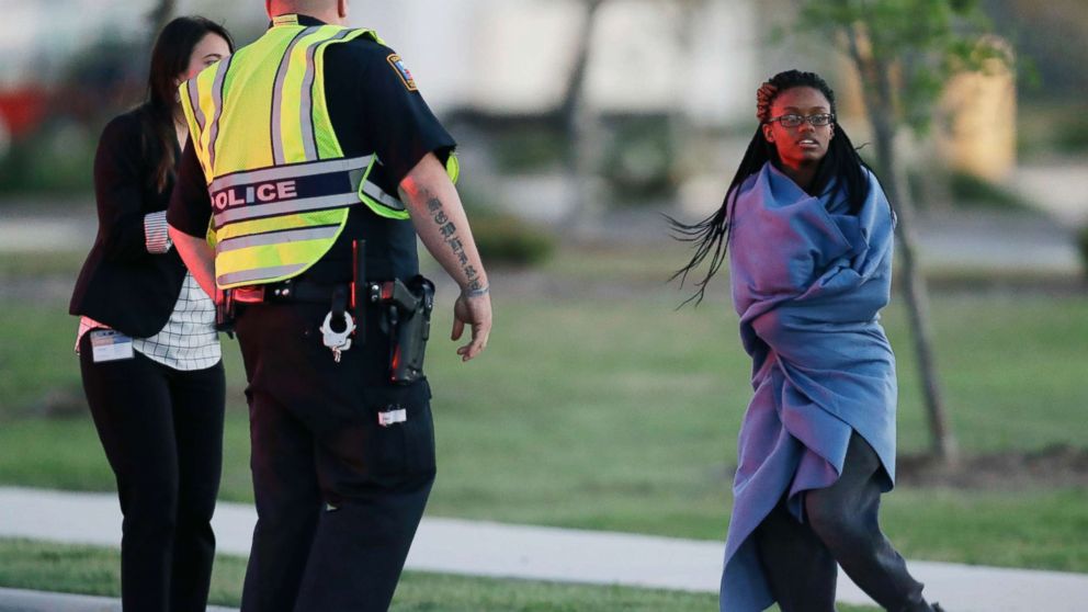 PHOTO: An employee wrapped in a blanket talks to a police officer after she was evacuated at a FedEx distribution center where a package exploded, March 20, 2018, in Schertz, Texas.