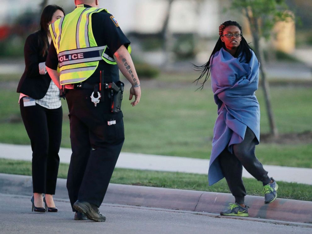 PHOTO: An employee wrapped in a blanket talks to a police officer after she was evacuated at a FedEx distribution center where a package exploded, March 20, 2018, in Schertz, Texas.
