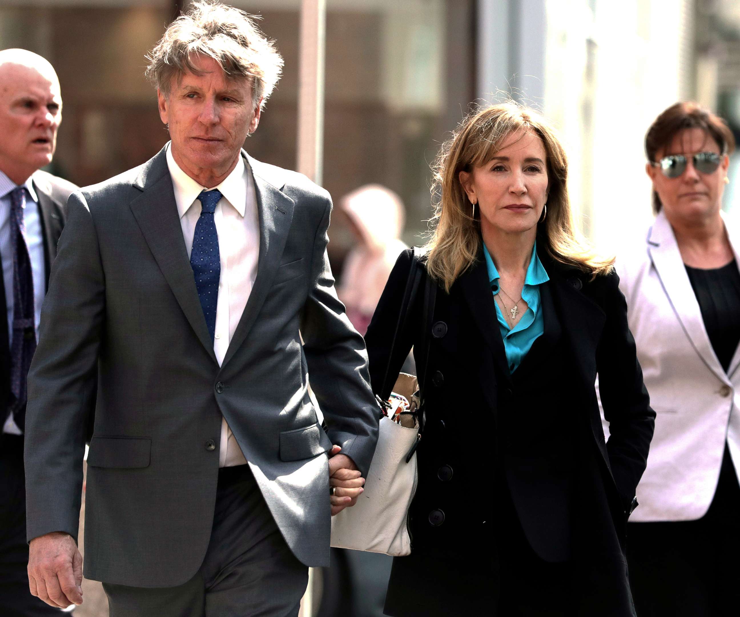 PHOTO: Felicity Huffman arrives holding hands with her brother Moore Huffman Jr., left, at federal court in Boston on Wednesday, April 3, 2019, to face charges in a nationwide college admissions bribery scandal.