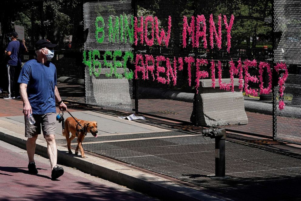 PHOTO: A man walks his dog past a sign marking the time a Minneapolis police officer had his knee on George Floyd's neck, along a fence erected near the White House in Washington, D.C., June 7, 2020.