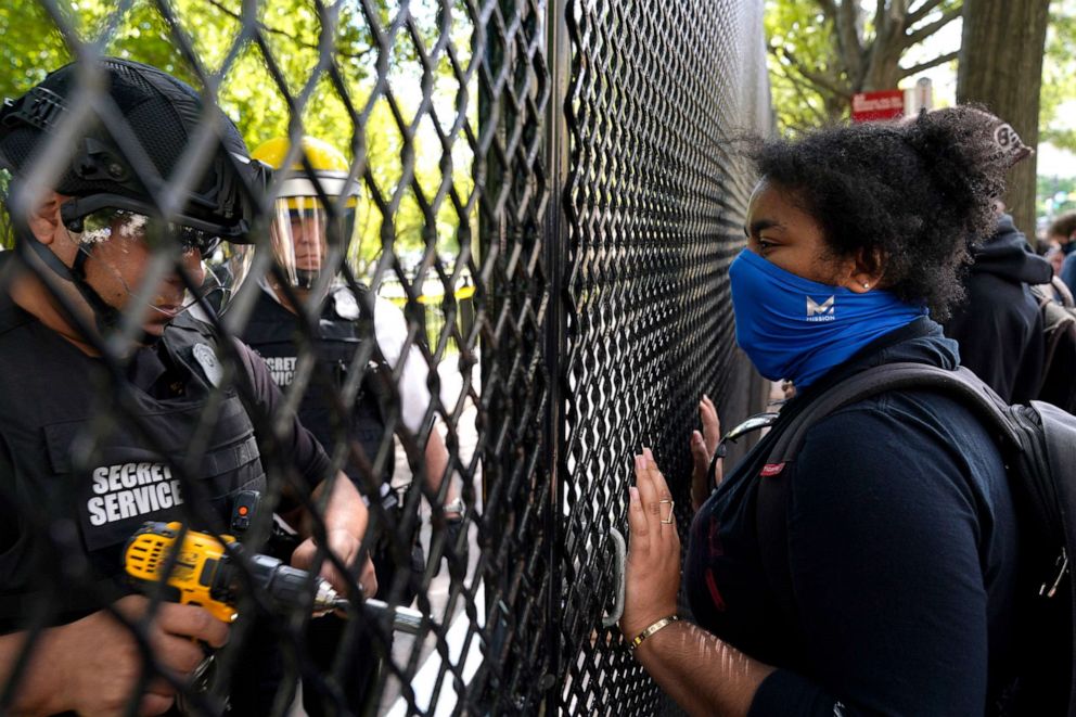 PHOTO:A demonstrator watches as a U.S. Secret Service police office works on a fence blocking Lafayette Park as protests in the death of George Floyd continue, June 2, 2020, near the White House in Washington, D.C. 