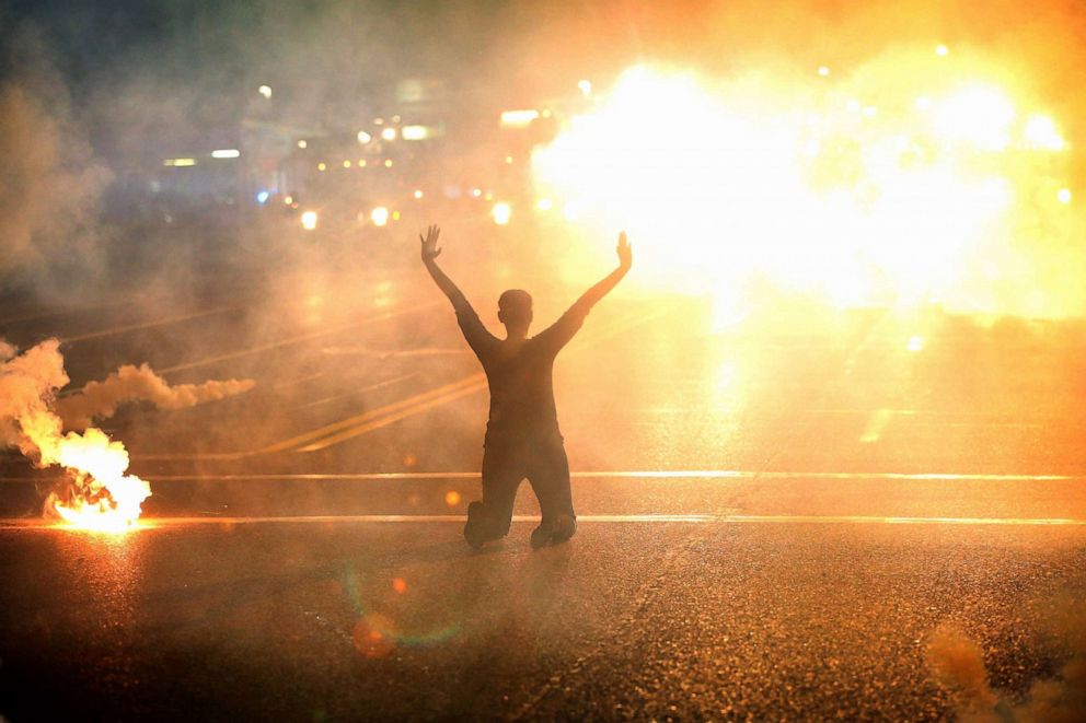 PHOTO: Tear gas reigns down on a woman kneeling in the street with her hands in the air after a demonstration over the killing of teenager Michael Brown by a Ferguson police officer, Aug. 17, 2014, in Ferguson, Missouri.