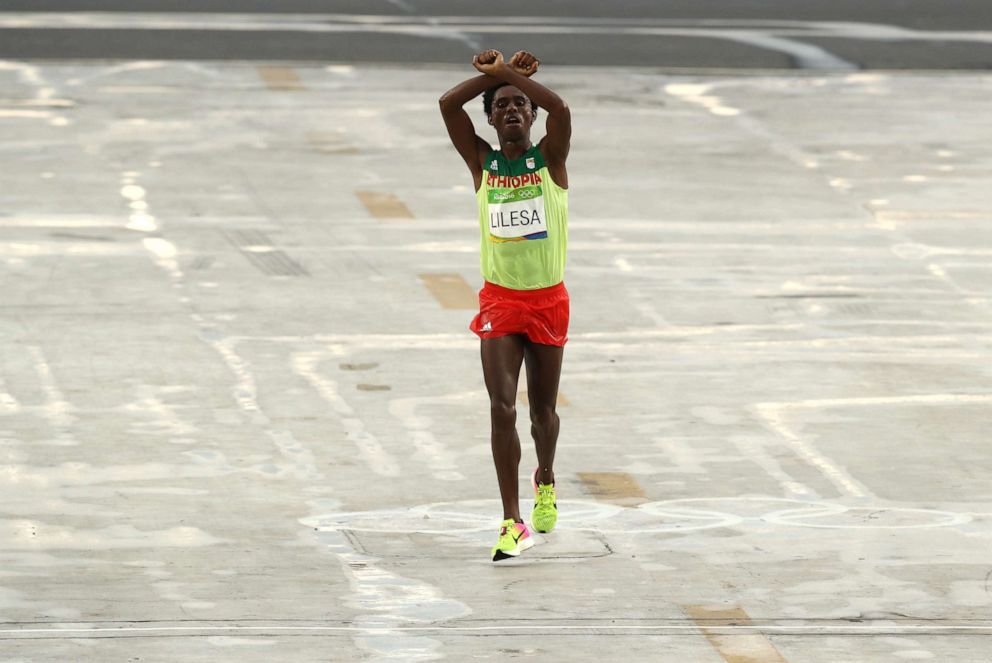 PHOTO: Feyisa Lilesa of Ethiopia crosses his arms as he crosses the finish line to win silver during the Men's Marathon on Day 16 of the Rio 2016 Olympic Games, August 21, 2016, in Rio de Janeiro.