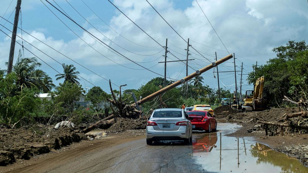 PHOTO: Cars drive under a downed power pole in the aftermath of Hurricane Fiona in Santa Isabel, Puerto Rico, Sept. 21, 2022. 