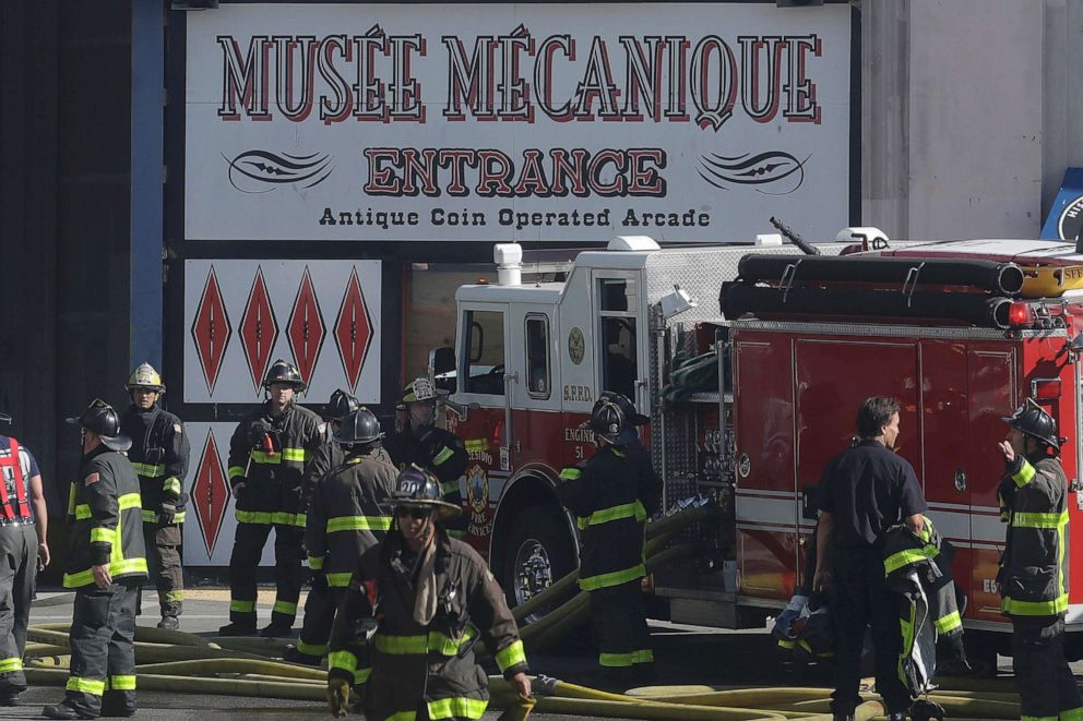 PHOTO: Fire officials work in front of a sign for Musee Mecanique after a fire broke out before dawn at Fisherman's Wharf in San Francisco, Saturday, May 23, 2020.