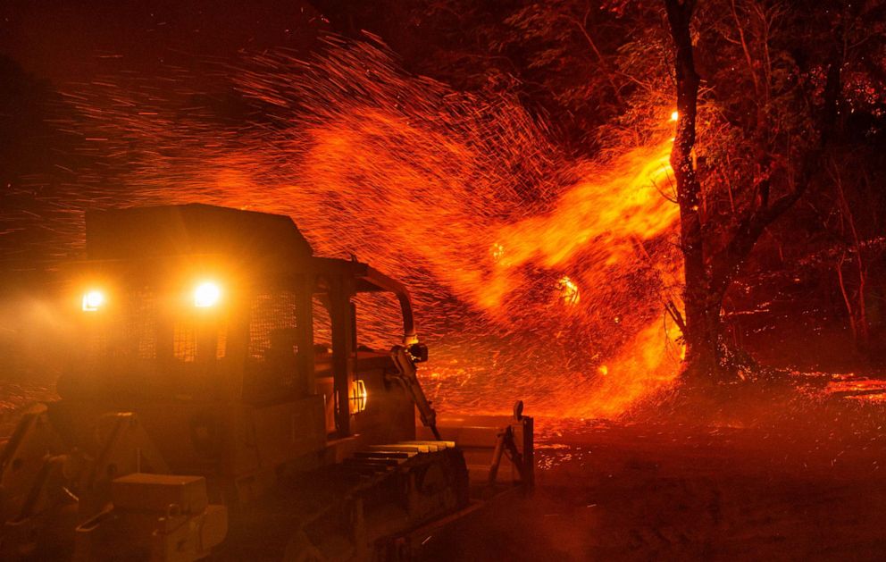 PHOTO: Embers fly off a tree as a bulldozer is prepared to help fight fire during the Kincade fire near Geyserville, California on October 24, 2019.