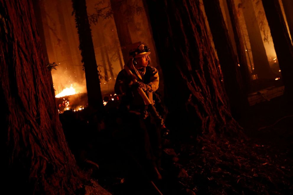 PHOTO: Cal Fire firefighter Anthony Quiroz carries a hose as he defends a home during the CZU Lightning Complex Fire in Boulder Creek, Calif. Aug. 21, 2020. 