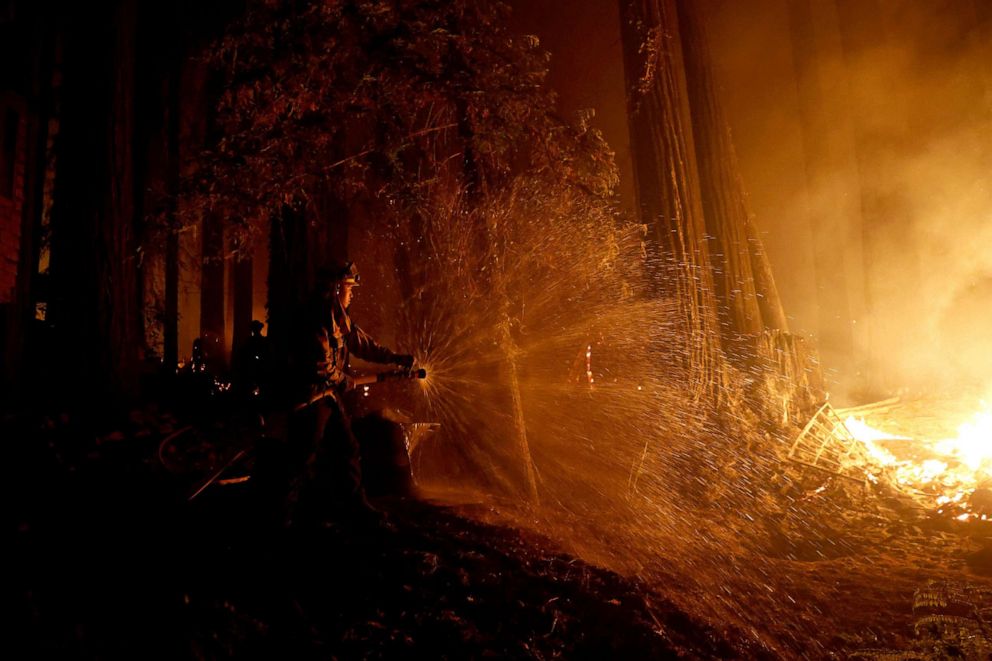 PHOTO: Cal Fire firefighter Anthony Quiroz douses water on a flame as he defends a home during the CZU Lightning Complex Fire in Boulder Creek, Calif., Aug. 21, 2020. 
