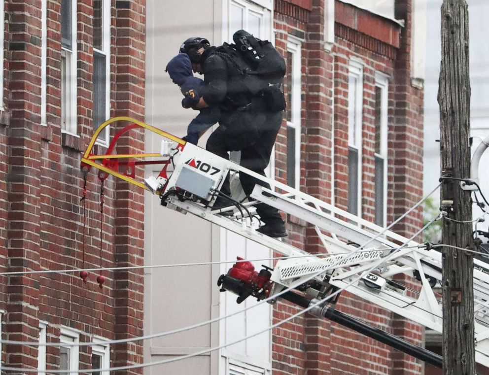 PHOTO: A child is taken from a third story window of an apartment building on Market Street in Wilmington, Del., by a police officer using a fire ladder truck, June 3, 2021, at the scene where three Wilmington police officers were shot the night before.