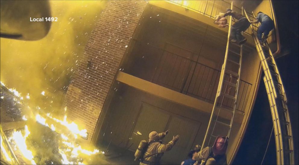 PHOTO: In a video caught by a helmet camera, firefighter Capt. Scott Stroup catches a young child dropped by a parent who was climbing down a ladder from a third-floor balcony early on Jan. 3, 2018.
