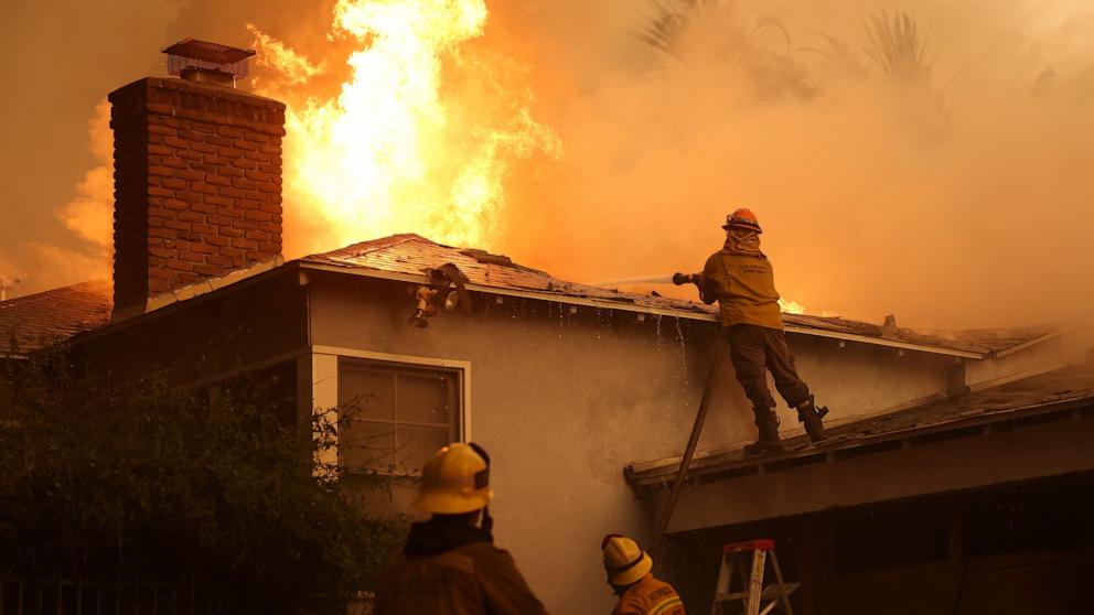 PHOTO: A Los Angeles County firefighter sprays water on a burning home as he battles the Eaton Fire, on Jan. 8, 2025, in Altadena, Calif.