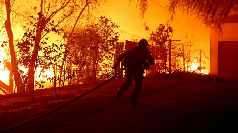 PHOTO: A firefighter pulls a hose while battling the Eaton Fire on Jan. 8, 2025, in Altadena, Calif.