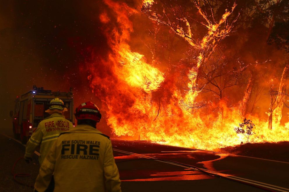 PHOTO: Fire and Rescue personal run to move their truck as a bushfire burns next to a major road and homes on the outskirts of the town of Bilpin on December 19, 2019 in Sydney, Australia.