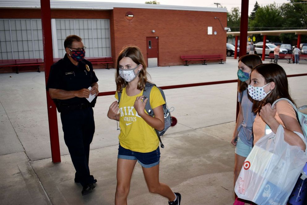 PHOTO: Students wearing masks enter Lewis and Clark Middle School for the first day of classes as a school resource officer looks on in Billings, Montana, on Aug. 24, 2020.