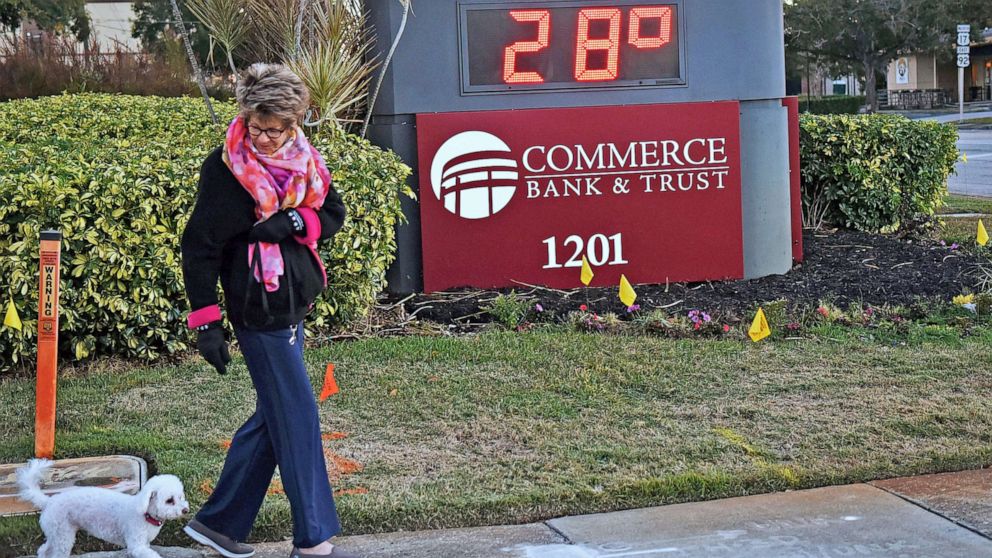 PHOTO: A woman walks her dog near a temperature sign reading 28 degrees in Winter Park, Fl, Jan. 30, 2022. Florida had its coldest weather in a decade, with temperatures near or below freezing in many parts of the state.