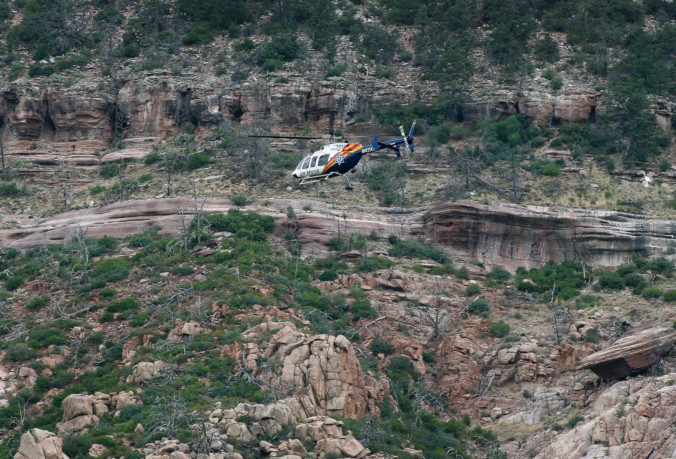 PHOTO: A helicopter flies above the rugged terrain along the banks of the East Verde River during a search and rescue operation for victims of a flash flood, July 16, 2017, in Payson, Ariz.