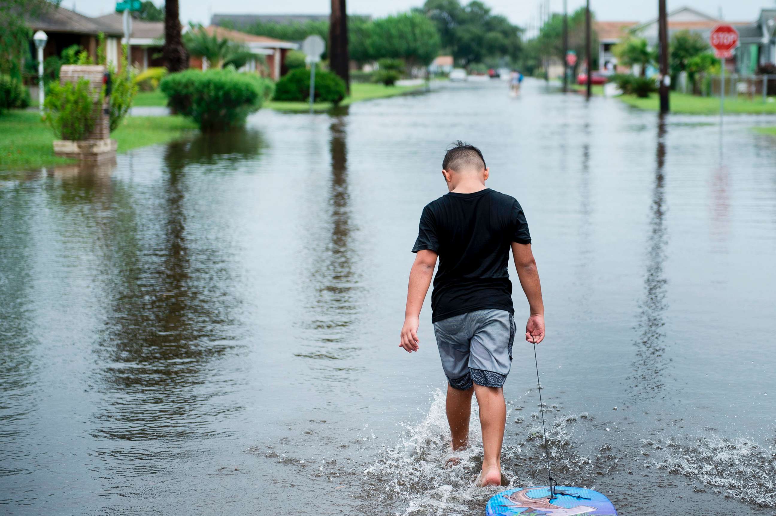 PHOTO: A boy walks with a bodyboard through a flooded street as the effects of Hurricane Harvey are seen Aug. 26, 2017 in Galveston, Texas.