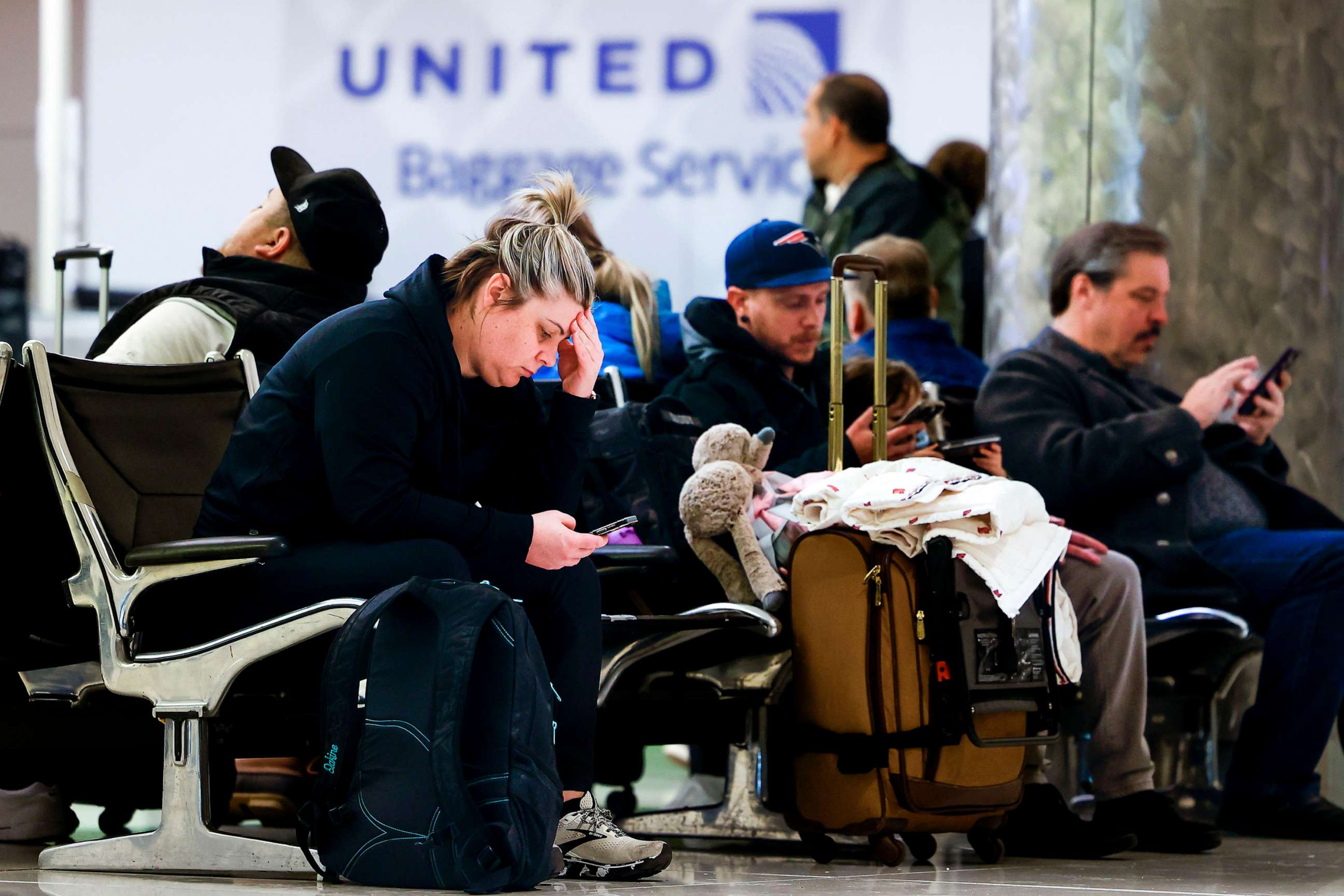 PHOTO: People sit at Denver International Airport amidst a wave of flight cancelations due to a winter storm, Feb. 22, 2023, in Denver.