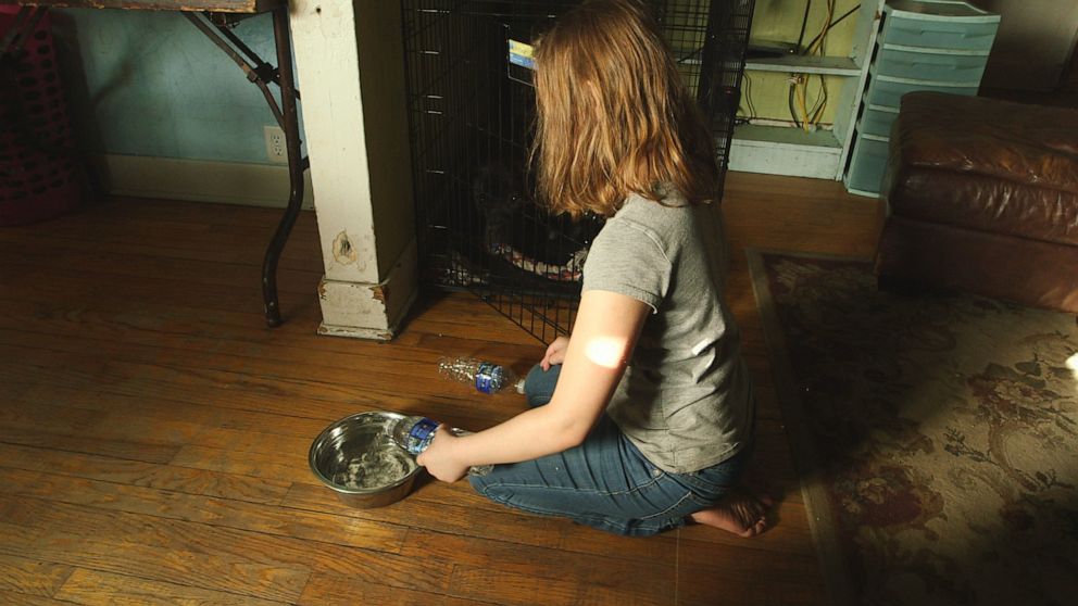 PHOTO: Eight-year-old Nala Uherek fills puppy Callie's bowl with bottled water at the family's home in Flint, Mich.