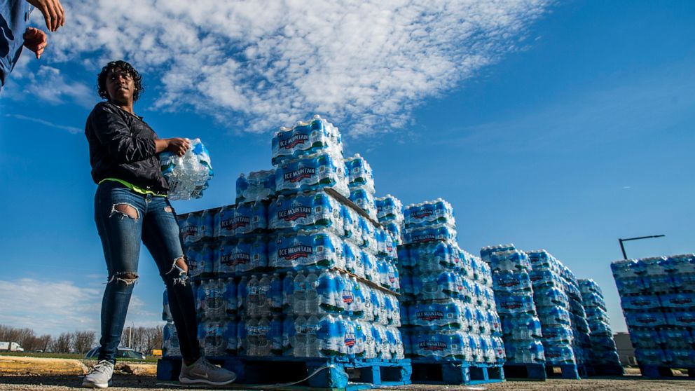 PHOTO: Volunteers load cases of water into vehicles in Flint, Mich., April 22, 2020.