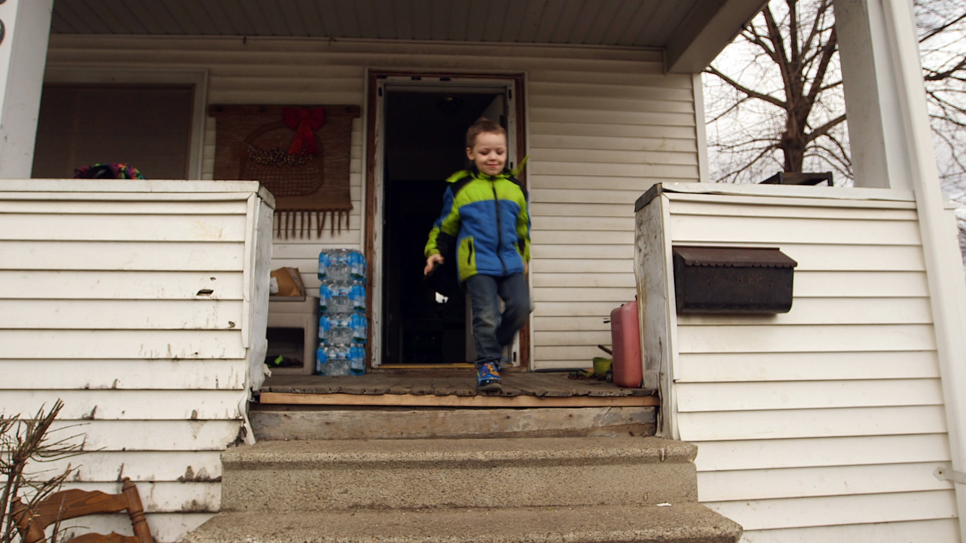 PHOTO: Four-year-old Michael Uherek runs to the car as cases of water bottles collected from a distribution center sit outside his family's home in Flint, Mich.