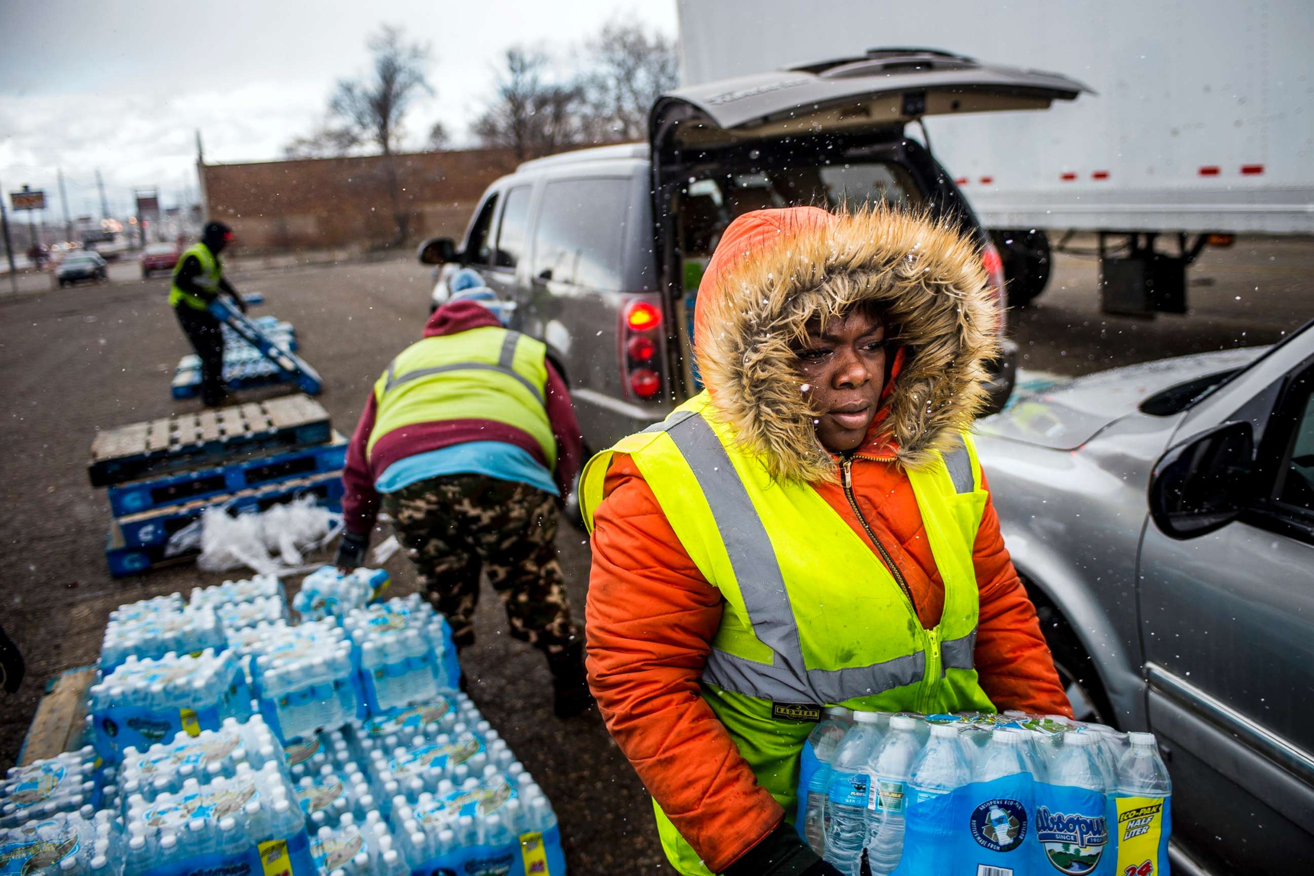 PHOTO: Flint resident Nia Augustine, 26, carries two cases of free bottled water as she fills a vehicle's trunk with eight cases at a water distribution center while cars line up more than 50 deep on Dort Highway, April 6, 2018 in Flint, Mich.