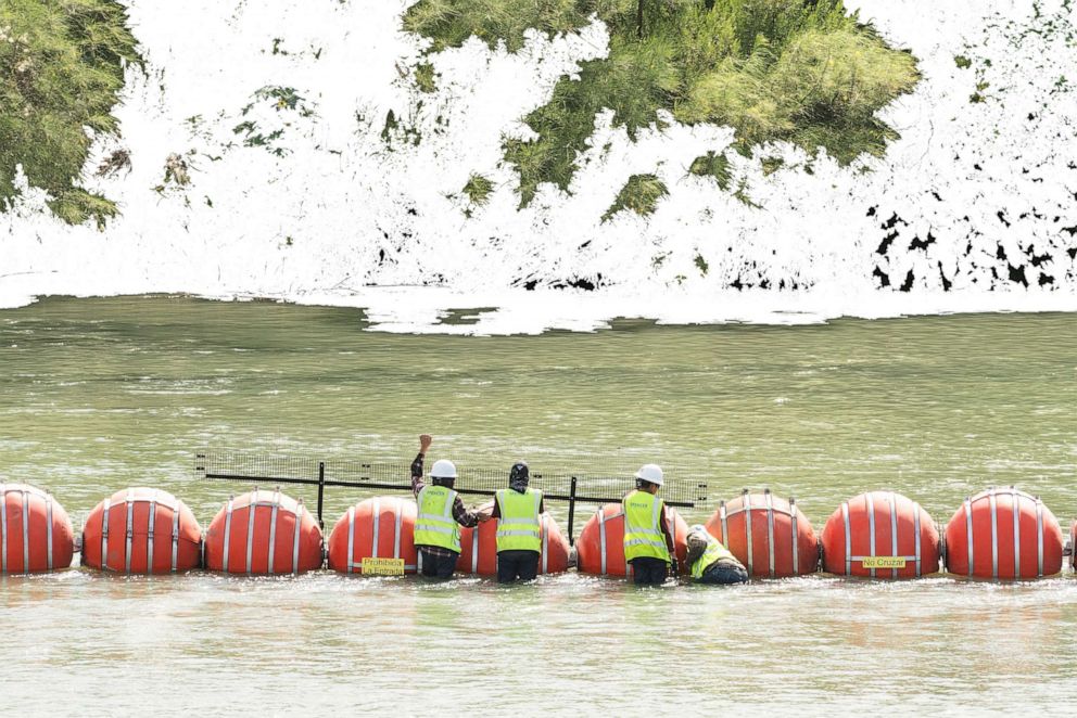 PHOTO: Workers install connected buoys, a measure by Texas authorities in an attempt to deter migrants from crossing the border, in the Rio Grande in Eagle Pass, Texas, on July 24, 2023.